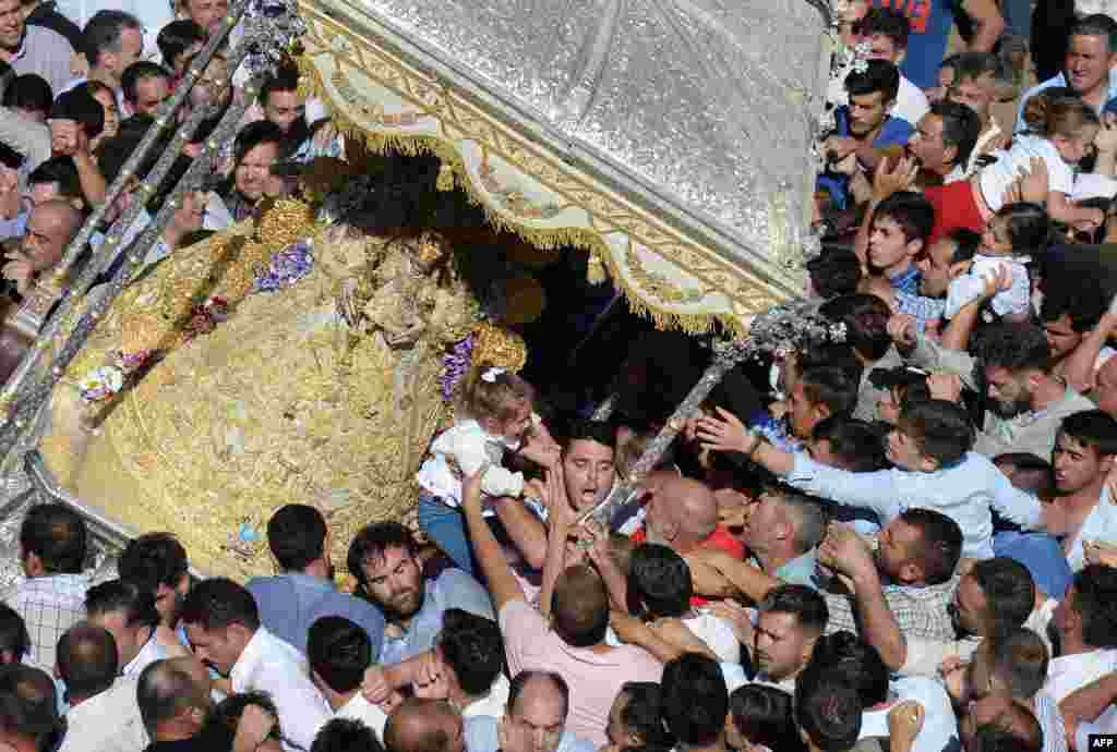 People touch an effigy the Rocio Virgin during a procession at the village of El Rocio, Spain.