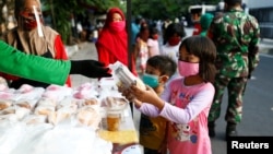 Anak-anak mengenakan masker menerima bantuan makanan gratis di tengah pandemi virus corona (Covid-19) di Jakarta, 14 Mei 2020. (Foto: Reuters)