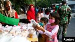 Anak-anak mengenakan masker menerima bantuan makanan gratis di tengah pandemi virus corona (Covid-19) di Jakarta, 14 Mei 2020. (Foto: Reuters)