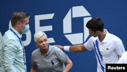 novak Đoković (desno) stoji pored linijske sudije koju je nenamerno pogodio lopticom u grlo, 6. septembra 2020. (Credit: Danielle Parhizkaran-USA TODAY Sports)