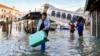 Orang-orang mengarungi air pasang di dekat Jembatan Rialto di Venesia, Italia, 23 Desember 2019. Sedikitnya delapan orang tewas akibat hujan lebat semalam dan banjir di kawasan Marche, Italia Tengah, pada 16 September 2022. (Foto: AP)