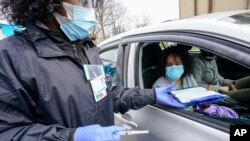 FILE - A nurse takes paper work from a woman before inoculating her with a COVID-19 vaccine, at the Uniondale Hempstead Senior Center, in Uniondale, New York, March 31, 2021. 