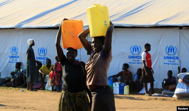 FILE - Women who fled fighting in South Sudan carry water in plastic container on arrival at Bidi Bidi refugee’s resettlement camp near the border with South Sudan, in Yumbe district, northern Uganda, Dec. 7, 2016.