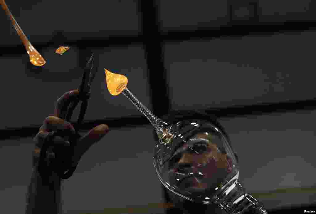 A master glassmaker adds fused material to form the base of a handmade gin-tonic glass at Royal Crystal Factory in La Granja de San Ildefonso, near Madrid, Spain, Nov. 12, 2013.