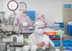 FILE - Workers produce face masks for export, at a factory in Nantong, in China's eastern Jiangsu province, May 14, 2020.
