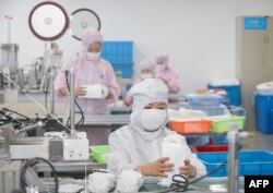 FILE - Workers produce face masks for export, at a factory in Nantong, in China's eastern Jiangsu province, May 14, 2020.