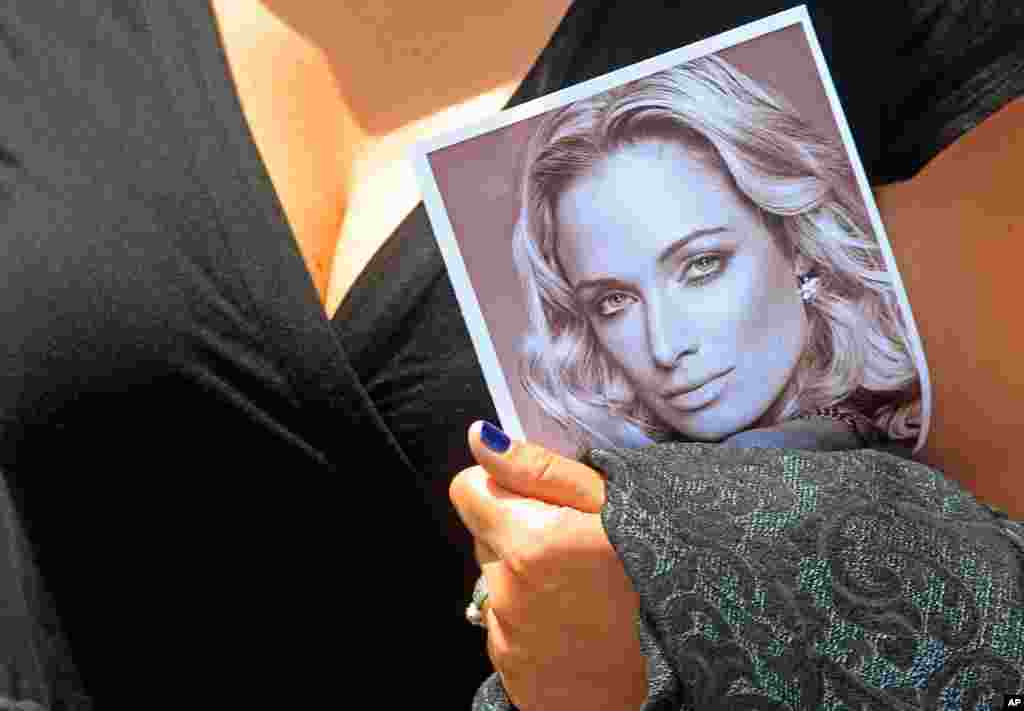 A woman holds a photo of Reeva Steenkamp as she leaves her funeral in Port Elizabeth, South Africa, February 19, 2013.