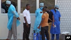 In this photo taken on March 29, 2014, medical personnel at the emergency entrance of a hospital receive suspected Ebola virus patients in Conakry, Guinea.