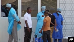 Petugas medis rumah sakit di Conakry, Guinea, menyambut pasien-pasien yang diduga terkena virus Ebola (29/3). (AP/Youssouf Bah)