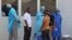 In this photo taken on March 29, 2014, medical personnel at the emergency entrance of a hospital receive suspected Ebola virus patients in Conakry, Guinea.