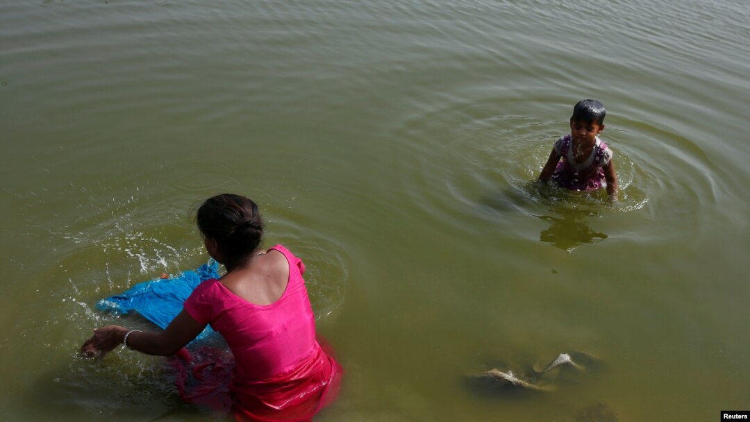 ARSIP – Seorang wanita mencuci pakaiannya dan putrinya mandi di Sungai Yamuna di hari yang panas di New Delhi, India, 24 April 2017 (foto: Reuters/Adnan Abidi)