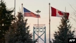 Bandeiras canadianas e americanas hasteadas no lado canadiano da ponte Ambassador em Windsor, Ontário, a 8 de março de 2025.