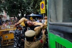 FILE - Police detain an activist during a protest demanding the resignation of Home Minister Amit Shah following clashes between people demonstrating for and against a new citizenship law in New Delhi, India, March 2, 2020.