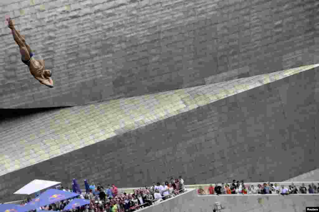 A contestant dives from a 27-meter platform on the La Salve bridge overlooking the Guggenheim Museum during the finals of the Red Bull Cliff Diving series in Bilbao, Spain, June 30, 2018.