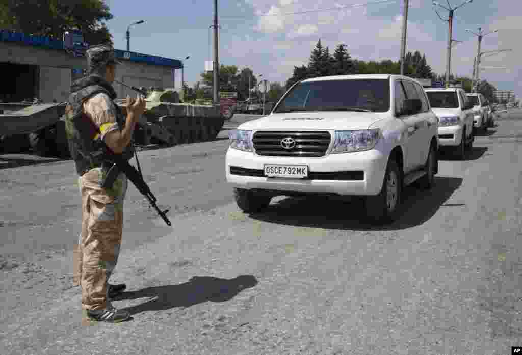 An Ukrainian government army soldier stands guard next to the convoy of the OSCE mission in Ukraine, at a check-point in the village of Debaltseve, Donetsk region, July 31, 2014.