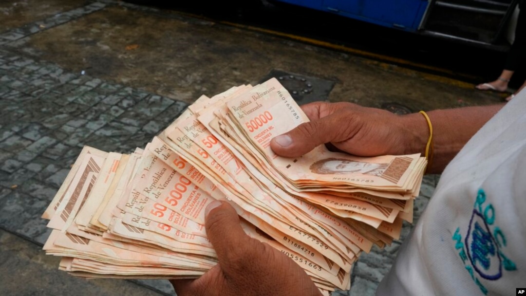 Un hombre cuenta billetes de bolívares venezolanos en una parada de autobús en Caracas. Agosto 5, 2021.