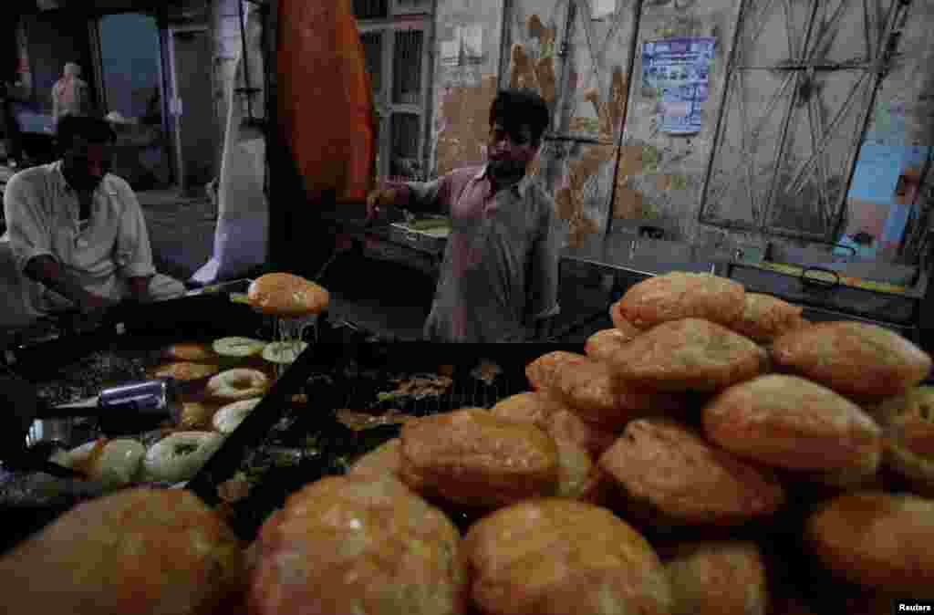 Para penjual menyiapkan "khajla", jajanan lokal yang biasa dikonsumsi sebagai hidangan berbuka puasa (Ta'jil) pada bulan Ramadan, di Karachi, Pakistan.