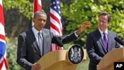 British Prime Minister David Cameron (R) watches U.S. President Barack Obama speak to reporters at Lancaster House in London, May 25, 2011