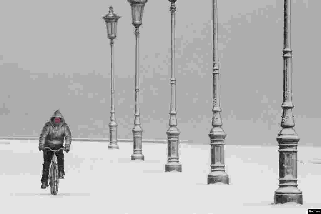 A man rides his bike during heavy snowfall at the seaside promenade of the northern port city of Thessaloniki, Greece.