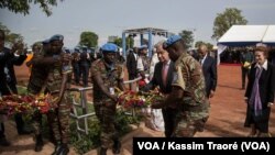 Le secrétaire général de l'ONU, Antonio Guterres, au milieu de deux casques bleus, déposent une gerbe de fleurs en mémoire des soldats onusiens décédés au Mali, 30 mai 2018. (VOA/Kassim Traoré)