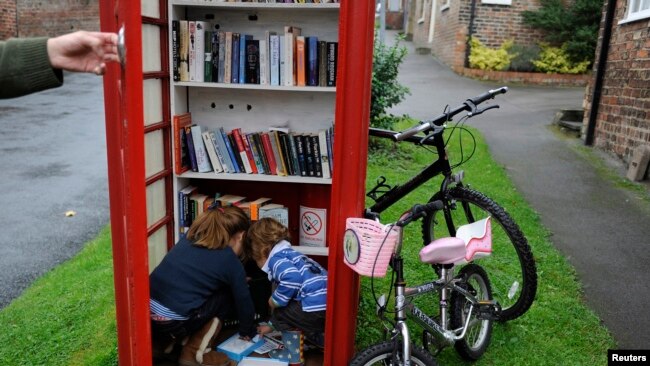 Bilik telepon umum warna merah di Inggris yang berubah fungsi menjadi perpustakaan di Marton cum Grafton, Inggris utara.