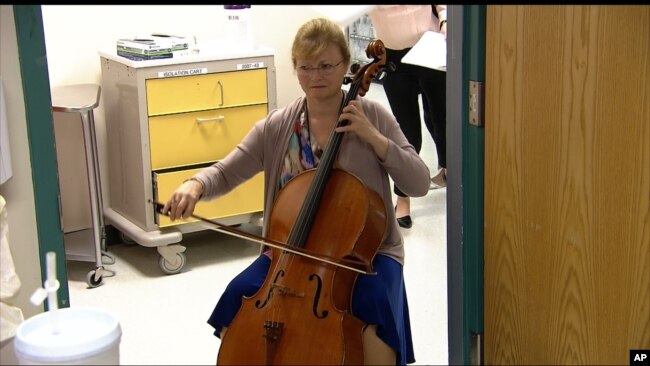 FILE - In this image taken from video, cellist Martha Vance plays for a patient at Medstar Georgetown University Hospital in Washington, Oct. 11, 2017.