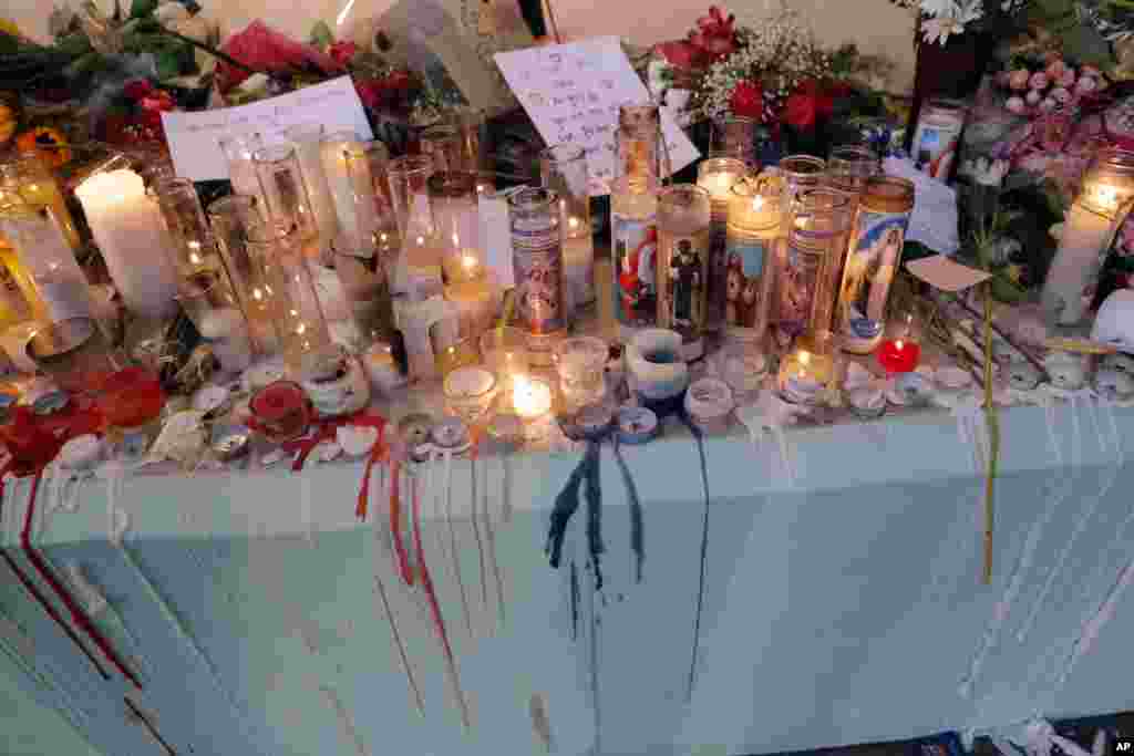 People pay homage with flowers and candles for the 17 deceased students and faculty from the Wednesday shooting at Marjory Stoneman Douglas High School, in Parkland, Fla., Feb. 16, 2018. 