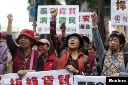 FILE - Activists shout during a protest against trade agreement with China in front of the Council of Agriculture in Taipei, Taiwan, January 4, 2016. The placards read, "Refuse trade agreement." "Trade agreement kill farmers."