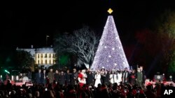 FILE - President Barack Obama, with Michelle Obama, and daughter Sasha, sing with Santa Claus and others during the lighting ceremony for the 2016 National Christmas Tree on the Ellipse near the White House, Dec. 1, 2016.