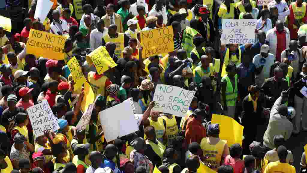 Des vendeurs de rue zimbabwéennes tiennent des banderoles, lors d'une manifestation à Harare, exhortant le gouvernement à cesser de les chasser, le mercredi juin 24, 2015