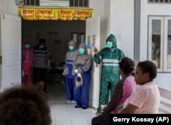 Petugas kesehatan menggunakan masker dan jas hujan sebagai antisipasi penyebaran virus corona baru di ruang tunggu Puskesmas, di Yalimo, Papua, Selasa, 21 April 2020. (AP Photo/Gerry Kossay)