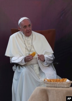 Pope Francis holds a piece of bread he blessed during his meeting with faithful in front of the shrine of St. Alberto Hurtado in Santiago, Chile, Jan.16, 2018.