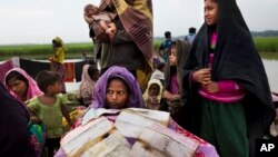 A Rohingya woman, who fled persecution in Myanmar, tries to dry her documents that got wet as she waits along the border for permission to move further towards refugee camps near Palong Khali, Bangladesh, Nov. 2, 2017.