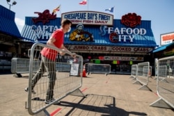 Stan Kiser with Jessie Taylor Seafood helps set up portable fencing in the hope to force customers to social distance at the Fish Market at The Wharf, April 6, 2020, in Washington.