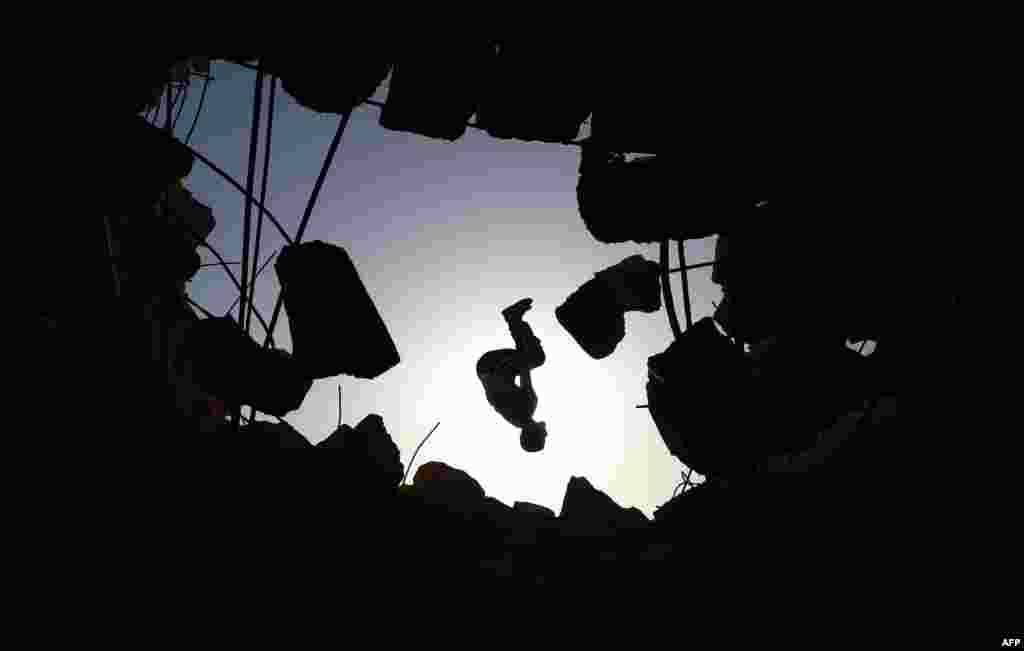 A young man performs a &quot;parcours,&quot; an obstacle course method derived from military training, over the ruins of a building destroyed by shelling pro-regime forces, in the town of Binnish in the Syria&#39;s northwestern Idlib province, June 17, 2020.