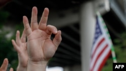 FILE - A demonstrator makes a hand gesture believed to have white supremacist connotations, Aug. 17, 2019, in Portland, Ore. The arrest of a U.S. soldier with far-right sympathies highlights a challenge for the Pentagon: purging its ranks of extremists.