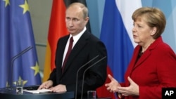 German Chancellor Angela Merkel, right, and President of Russia Vladimir Putin, left, address the media during a press conference after their meeting at the chancellery in Berlin, Germany, June 1, 2012.