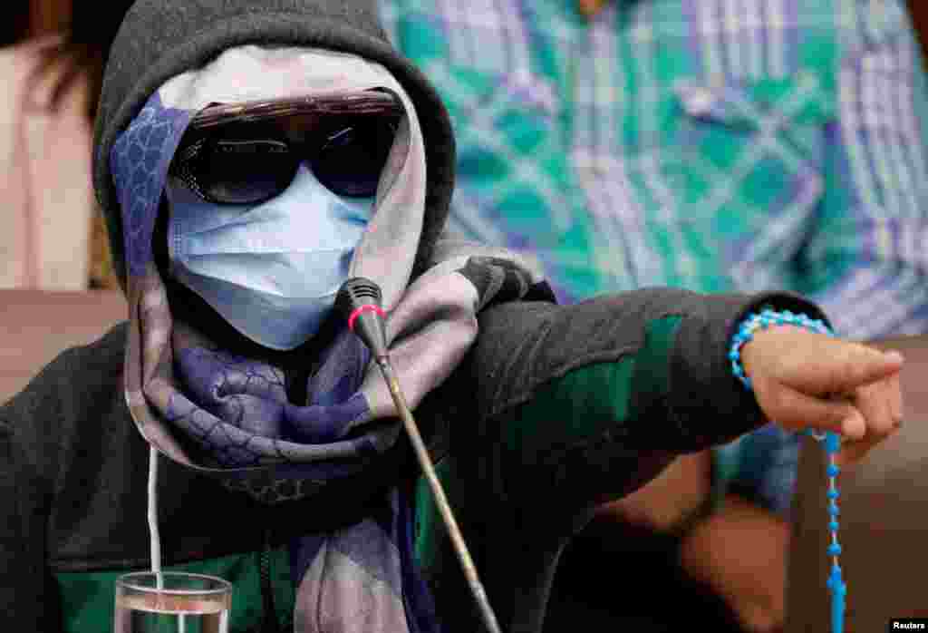 A masked witness points to the police officers suspected of killing 17-year-old Kian delos Santos as she testifies during a senate hearing in Pasay, Metro Manila, Philippines September 5, 2017. 