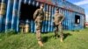 FILE - U.S. marines watch as members of Uganda's army undergo training in combat operation skills at a military training school in Singo, south of capital Kampala, April 30, 2012.