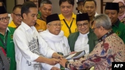 Indonesia's President Joko Widodo, front left, and the head of Indonesian Ulema Council Maruf Amin, center, submit their documents to election commission officials in Jakarta, Aug. 10, 2018, during their registration for the 2019 presidential election as president and vice president candidates.