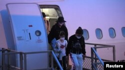 FILE - Australian evacuees who were quarantined on Christmas Island over concerns about the coronavirus disembark from a plane at Sydney Airport in Sydney, Australia, February 17, 2020.