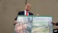 FILE - President Donald Trump holds an image of the border area as speaks during a tour to review border wall prototypes, March 13, 2018, in San Diego.