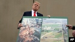 President Donald Trump holds an image of the border area as speaks during a tour as he reviews border wall prototypes, March 13, 2018, in San Diego, California. Trumps warns Mexico, April 3, 2018, that its free trade agreement would be jeopardized if it does not stop a caravan of Central American immigrants before it reaches the border with the U.S.