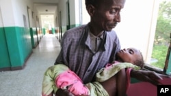 Un père portant son enfant à l'intérieur de l'hôpital Banadir, à Mogadiscio