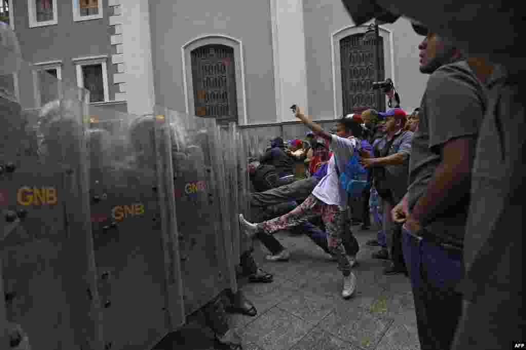 Supporters of Venezuelan Government clash with riot police before the National Assembly in Caracas. Opposition ratchets up the pressure on President Nicolas Maduro at mass protests, announcing plans for a general strike, a new march and a legislative onslaught.