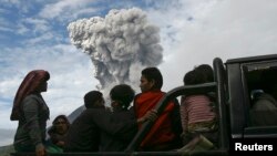 Warga desa duduk di truk saat melakukan evakuasi ke tempat aman, menyusul letusan Gunung Sinabung (24/11) di desa Aman Teran, kabupaten Karo, Sumatera Utara. (Reuters/YT Haryono)