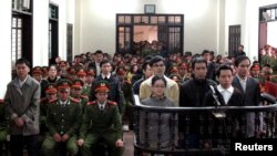 Dalam foto yang diambil oleh Kantor Berita Vietnam ini, para tergugat berdiri di depan dermaga di sebuah pengadilan di provinsi Nghe An, sekitar 300 kilometer selatan Hanoi, 9 Januari 2013. (REUTERS/Nguyen Van Nhat/Vietnam News Agency). Vietnam kembali mengadili 22 aktivis demokrasi atas tuduhan subversi, Senin (27/1).