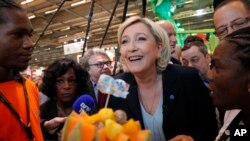 ຜູ້ນຳພັກຂວາຈັດຝຣັ່ງ ທ່ານນາງ Marine Le Pen ຍີ້ມຫົວຢູ່ ເກາະ Caraibean ຂອງຝຣັ່ງ ໃນຄະນະທີ່ທ່ານນາງໄປຢ້ຽມຢາມ .