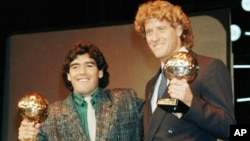 ARCHIVO - La estrella del fútbol argentino Diego Maradona, izquierda, y el portero de Alemania Occidental Harald Schumacher sostienen sus premios de Balón de la Copa Mundial de Fútbol, durante la ceremonia del Premio Bota de Oro de Fútbol, en París, el 13 de noviembre de 1986. 