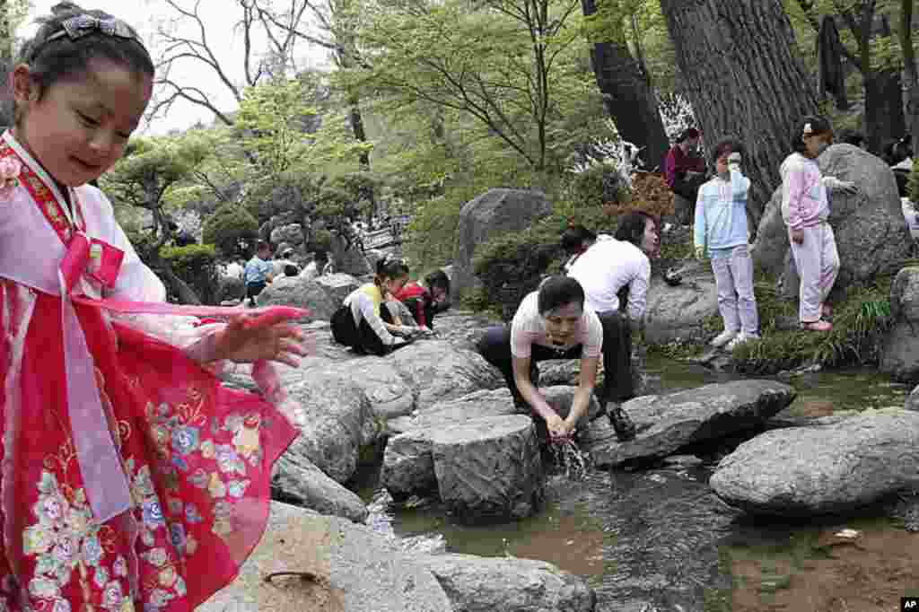 North Koreans dip their hands in a stream in Pyongyang, North Korea, on May Day, May 1, 2012. North Korean families flocked to parks, playgrounds and plazas to enjoy the May Day holiday with picnics, cultural events and games. (AP Photo)